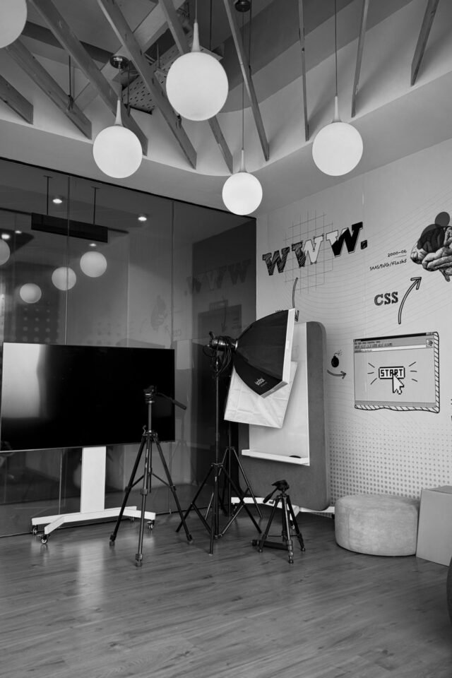 How to Hire a Webflow Designer in 2026: Costs, Where to Look, and How to Vet Minimalist workspace with a large screen, tripods, web design graphics, and pendant lights.